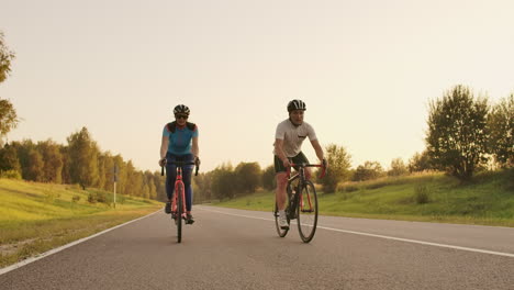 Steadicam-shot-of-mountain-biking-couple-riding-on-bike-trail-at-sunset-doing-high.